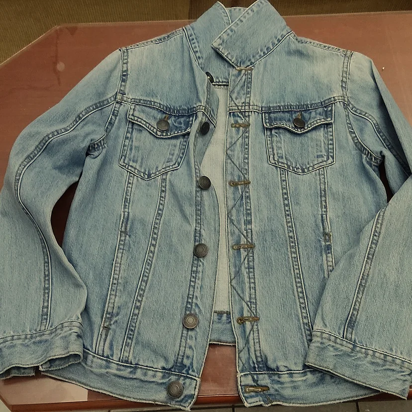 Veste en jean photographiée sous une lumière chaude : son bleu tire vers le vert-gris.